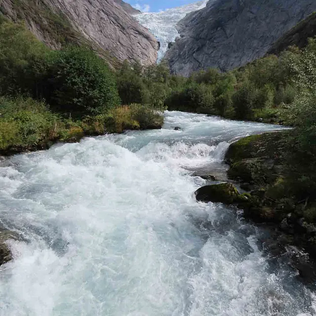 Stri og hvit skummende elv som renner gjennom en trang fjelldal.
