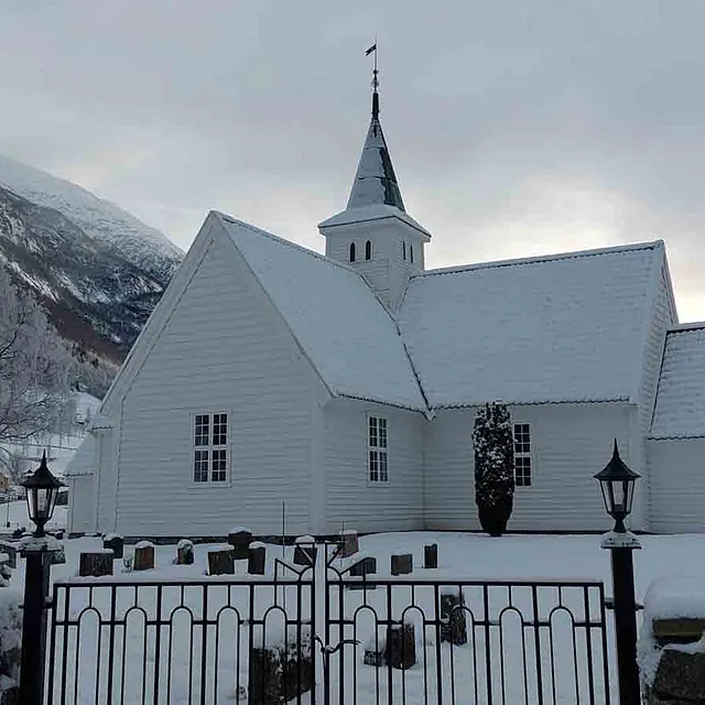 Hvit kirke med snølandskap og fjell