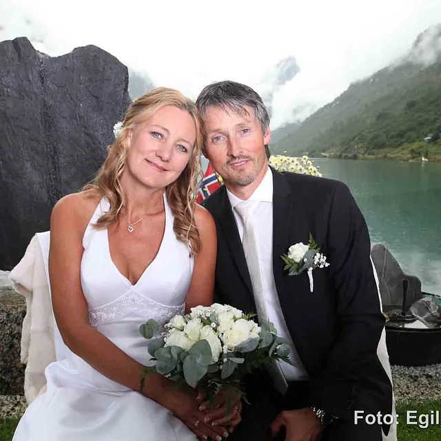 Brudepar sitter foran stein formet som hjerte